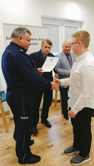 Komendant Powiatowy Policji w Lubaczowie wraz ze Starosta Lubaczowskim wręczają nagrodę laureatowi konkursu.