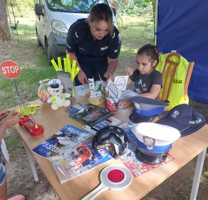 Na zdjęciu policjantka w umundurowaniu służbowym wraz z uczestniczką pikniku rozmawiają przy stoisku policji.