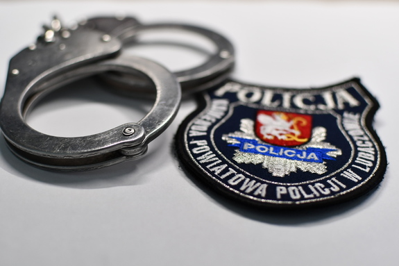 Na zdjęciu kajdanki i emblemat z logiem i napisem Komenda Powiatowa Policji w Lubaczowie.