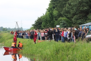 Na zdjęciu w tle uczestnicy pokazu, na pierwszym planie strażacy w łódce.