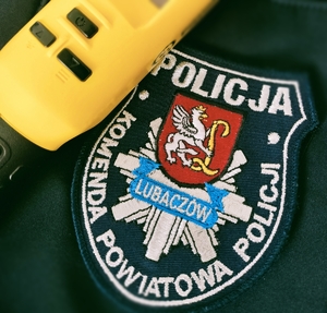 Na zdjęciu urządzenie w kolorze żółtym  do sprawdzania stanu trzeźwości, na tle emblematu Komendy Powiatowej Policji w Lubaczowie.