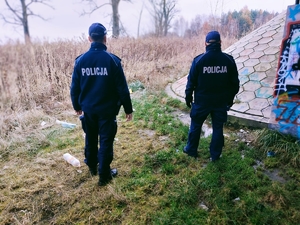 Na zdjęciu policjanci w umundurowaniu służbowym sprawdzają miejsca , gdzie mogą znajdować się osoby narażone na wychłodzenie organizmu.