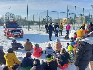 Na zdjęciu grupa uczniów wraz z policjantami oraz strażakami OSP, w trakcie przeprowadzania prelekcji na temat bezpiecznych ferii.