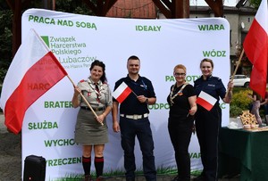 Na zdjęciu umundurowani policjanci i wraz z uczestnikami trzymającymi flagę Polski.