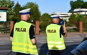 Na zdjęciu umundurowani policjant ruchu drogowego w kamizelce odblaskowej dokonujący pomiaru prędkości.