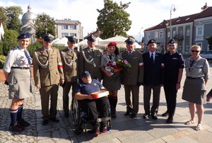 zdjęcie przedstawiające uczestników wydarzenia harcerka trzyma kwiaty.