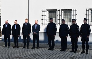 Na tle budynku stoją włodarze samorządów lokalnych oraz umundurowani policjanci.