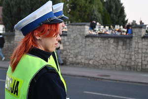 Policjanci z Ruchu Drogowego w umundurowaniu służbowym, w tle cmentarz.