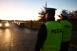 Policjanci ruchu drogowe, w tle ludzie, samochody, cmentarz.