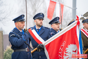 Poczet sztandarowy ze sztandarem w umundurowaniu galowym w postawie na baczność.