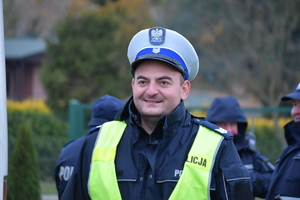 Policjant ruchu drogowego w białej czapce i kamizelce odblaskowej.