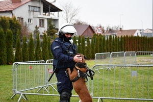 Przewodnik psa z psem służbowym, w tle boisko.