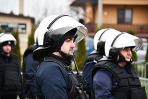 Policjanci w umundurowaniu i zestawie przeciwuderzeniowym.