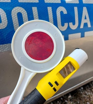 Na zdjęciu napis policja, tarcza do zatrzymywania pojazdów i alkomat.