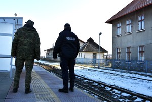 Policjant i strażnik graniczny stoją przy torowisku.