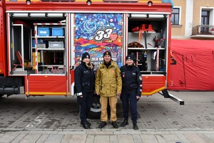 Policjantki i strażak na tle samochodu strażackiego.