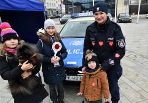 Policjantka i dzieci na tle radiowozu.