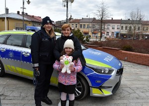 Policjantka kobieta i dziecko przed radiowozem.