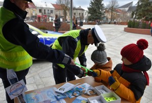 Policjanci z ruchu drogowego dają dzieciom odblaski.