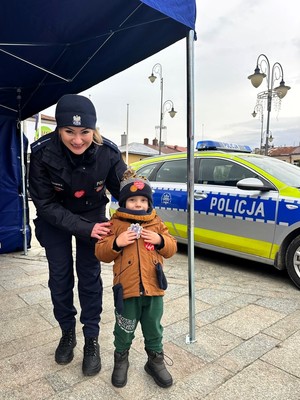 Policjantka i dziecko przed radiowozem.