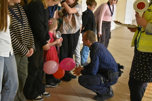 Dzieci uczestniczące w spotkaniu i policjanci w umundurowaniu służbowym.