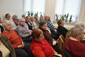 Seniorzy siedzący na sali.