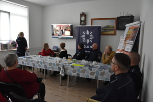 Prelegenci i uczestnicy oglądają film o oszustwach.