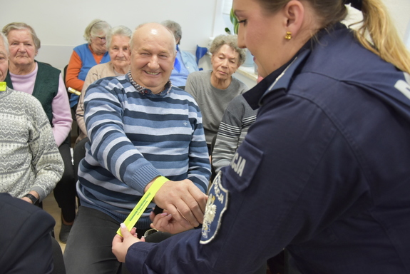 Senior i policjantka zakładająca mu odblask.