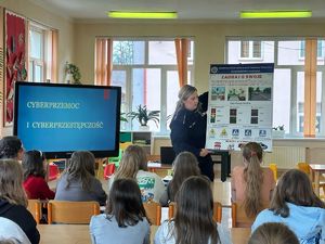 Umundurowana policjantka prezentuje dzieciom plansze edukacyjne z zasadami bezpieczeństwa.