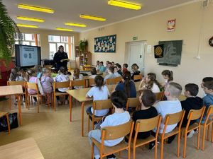 Umundurowana policjantka prezentuje dzieciom elementy odblaskowe.