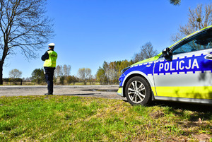 Policjant i radiowóz droga i las.