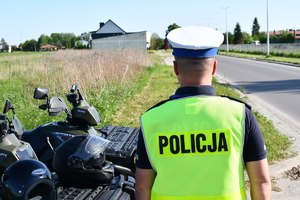 Policjant w umundurowaniu służbowym przy drodze.
