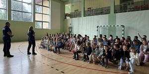 Dzieci, policjant, policjantka w hali sportowej.