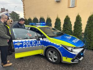 Uczestnicy oglądający oznakowany radiowóz policji.