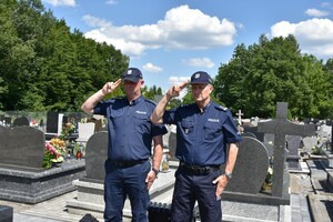 Policjanci na cmentarzu i znicz.